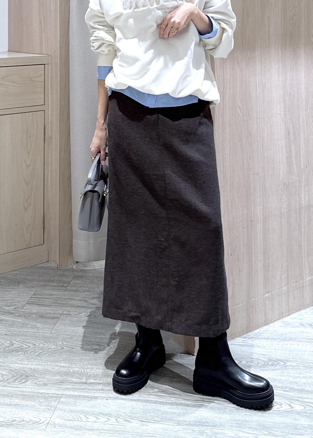 グレー系のショルダーバッグ、ブラック系のブーツ、ブラウン系のスカートを着用したレディースの秋コーディネートの5枚目の写真