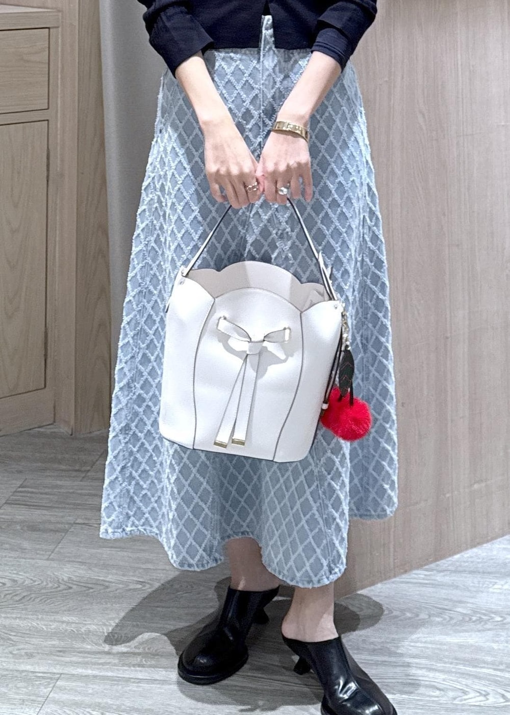 ホワイト系のショルダーバッグ、ブルー系のカーディガン/ボレロ、ブルー系のデニムスカートを着用したレディースの冬コーディネートの4枚目の写真