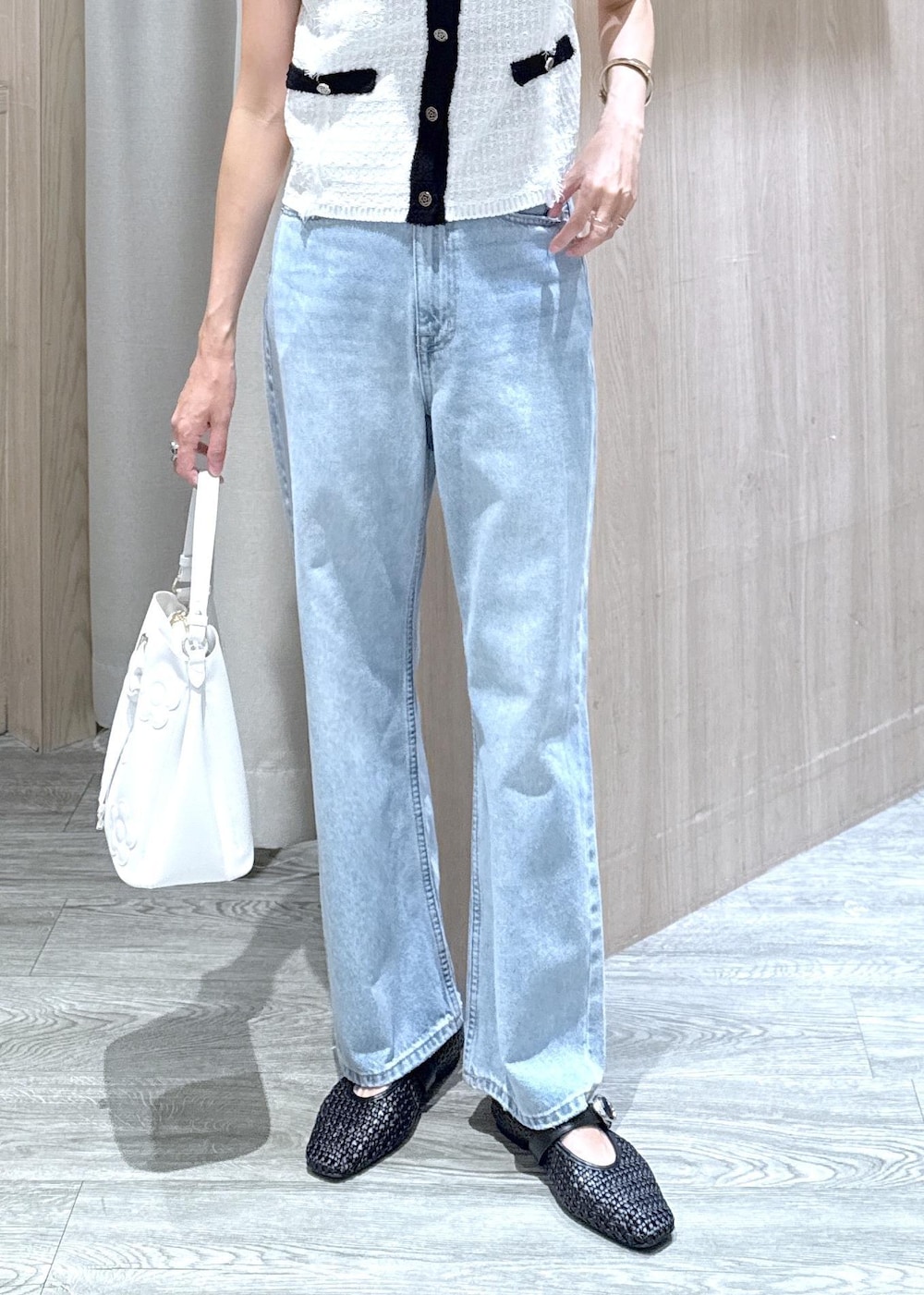 ブラック系のパンプス、ブルー系のデニムパンツ、ホワイト系のベストを着用したレディースの夏コーディネートの5枚目の写真