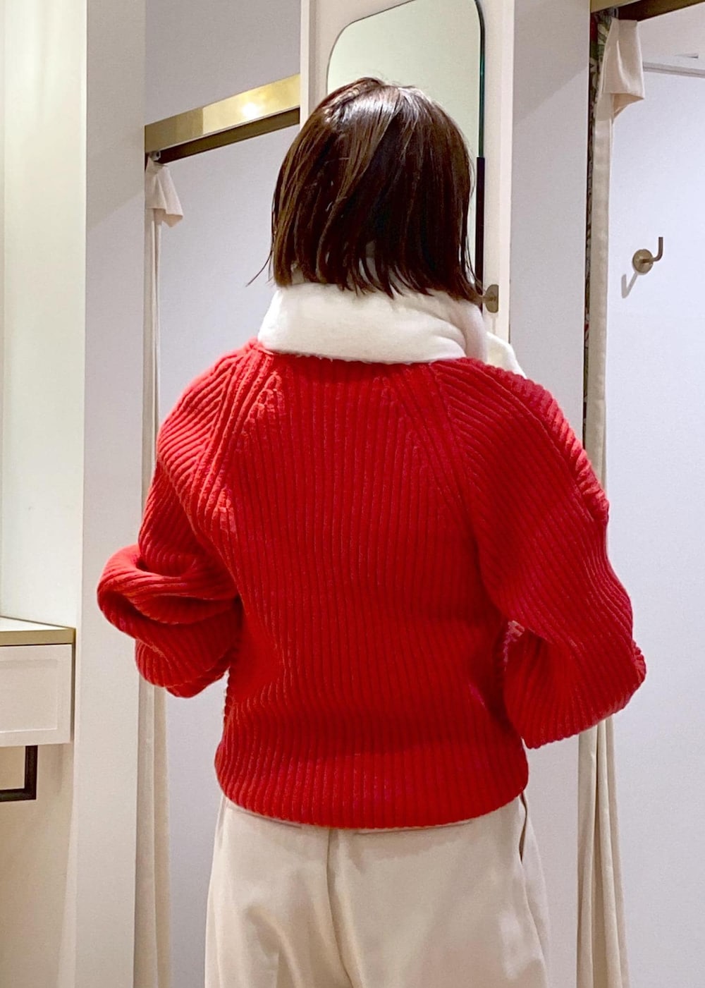 レッド系のニット/セーター、ホワイト系のスラックス、ブラック系のショルダーバッグを着用したレディースの冬コーディネートの7枚目の写真