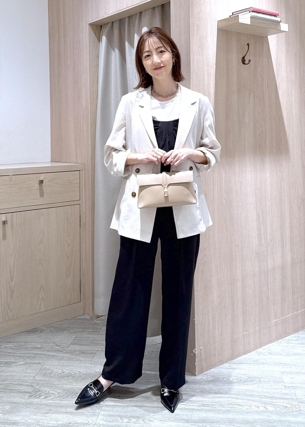 ベージュ系のショルダーバッグ、ブラック系のパンプス、ホワイト系のテーラードジャケットを着用したレディースの春コーディネートの2枚目の写真