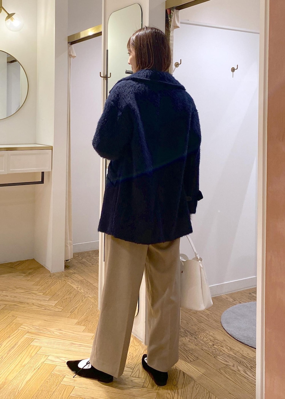 ホワイト系のショルダーバッグ、ベージュ系のスラックス、グレー系のカーディガン/ボレロを着用したレディースの冬コーディネートの2枚目の写真