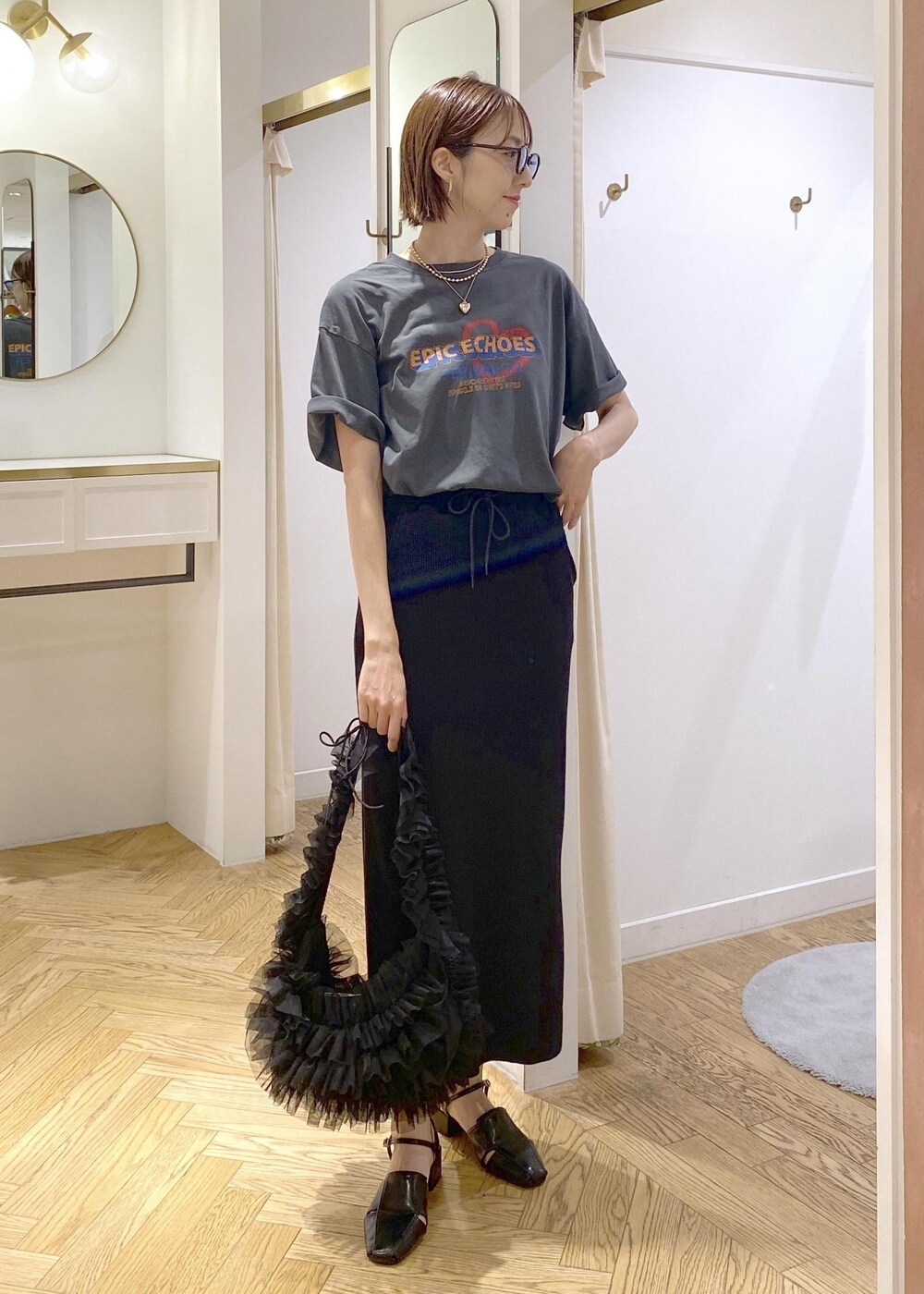 ブラック系のショルダーバッグ、ブラック系のスカート、グレー系のTシャツ/カットソーを着用したレディースの夏コーディネートの3枚目の写真