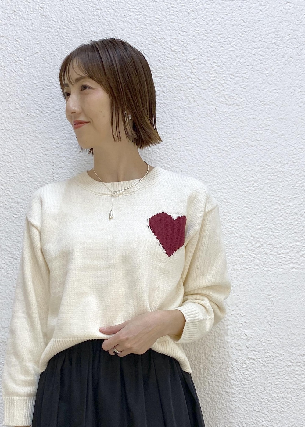 ブラック系のブーツ、ブラック系のスカート、グリーン系のショルダーバッグを着用したレディースの冬コーディネートの3枚目の写真