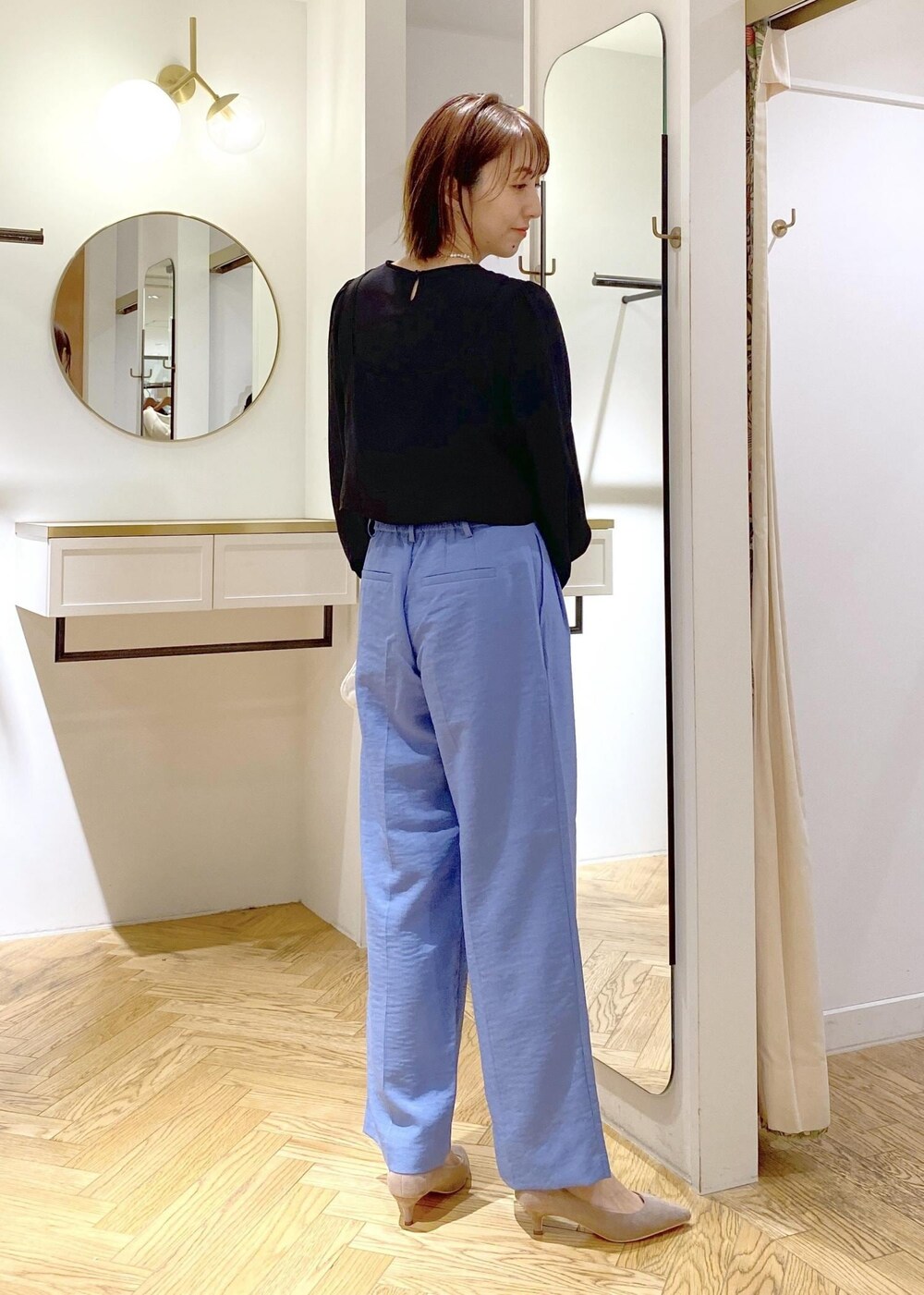 ホワイト系のショルダーバッグ、ブルー系のスラックス、ブラック系のシャツ/ブラウスを着用したレディースの春コーディネートの2枚目の写真