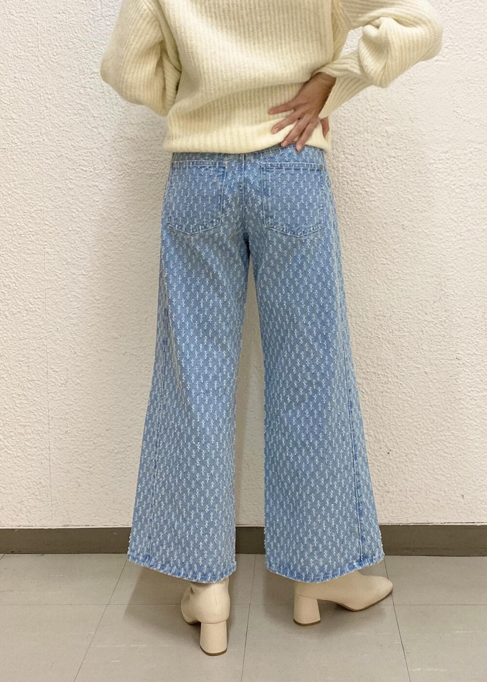 シルバー系のハンドバッグ、ホワイト系のニット/セーター、ブルー系のデニムパンツを着用したレディースの冬コーディネートの5枚目の写真