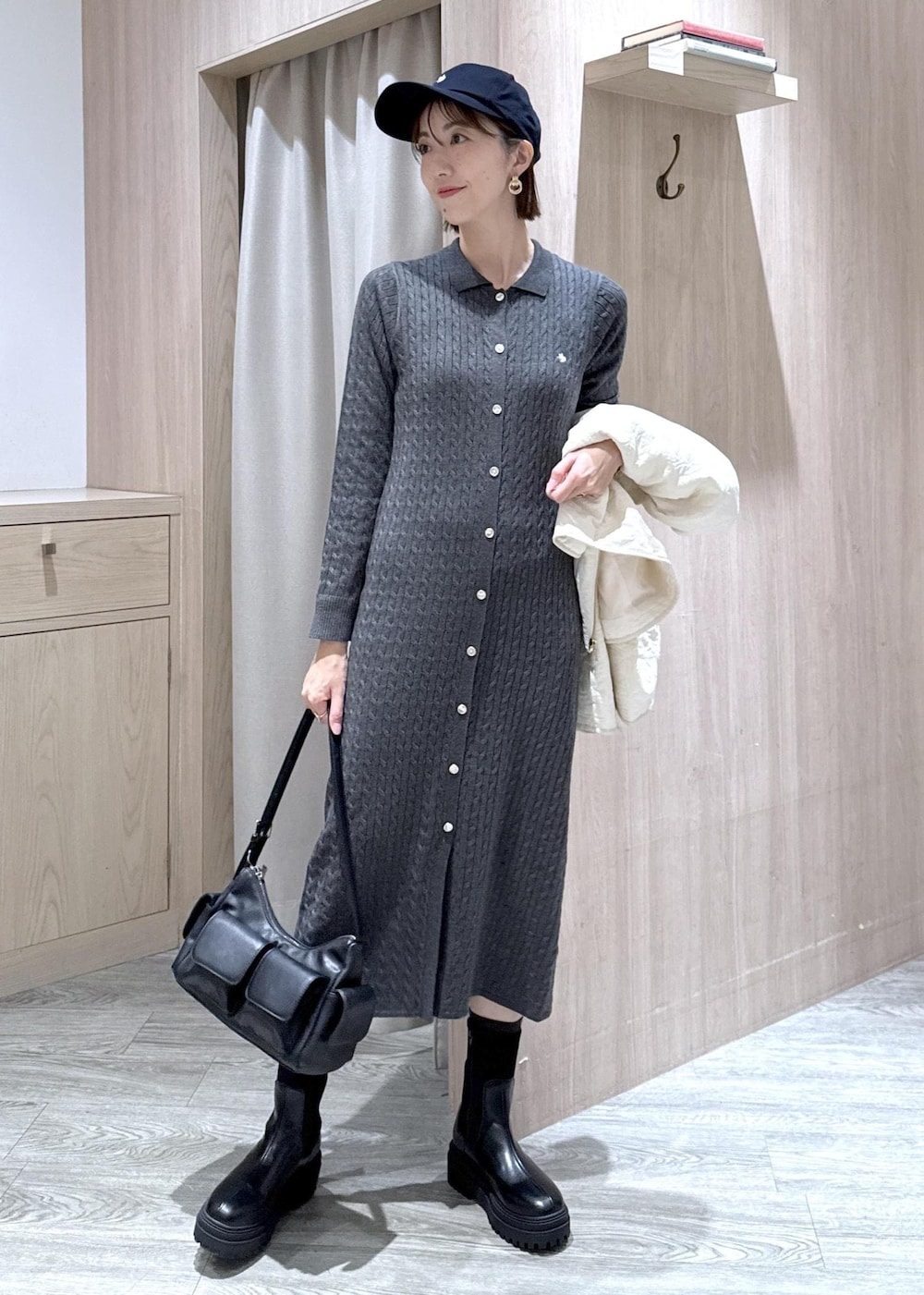 ブラック系のショルダーバッグ、ブラック系のブーツ、ホワイト系のブルゾンを着用したレディースの秋コーディネートの8枚目の写真