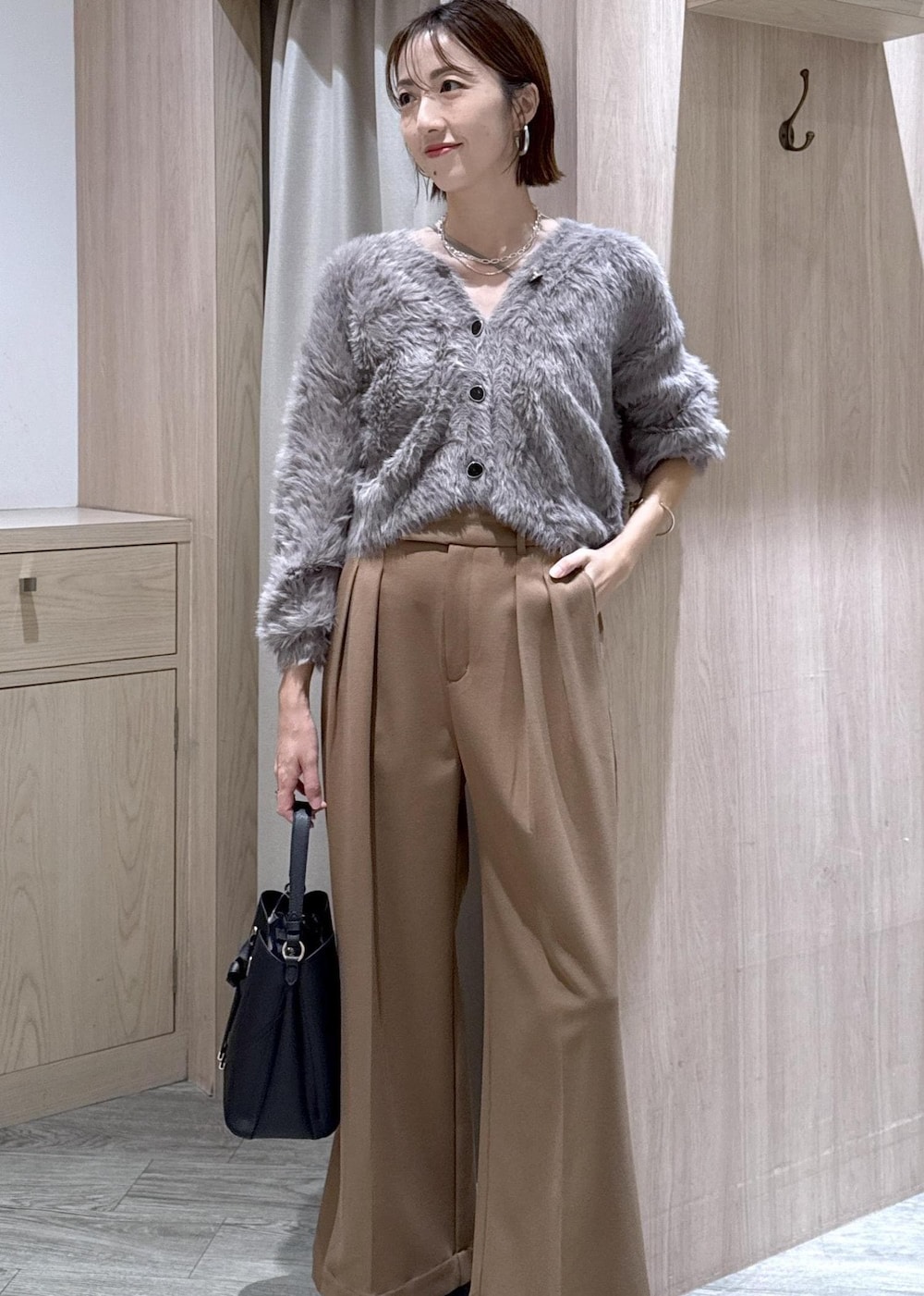 ブラック系のショルダーバッグ、グレー系のカーディガン/ボレロ、ブラック系のブーツを着用したレディースの秋コーディネートの3枚目の写真