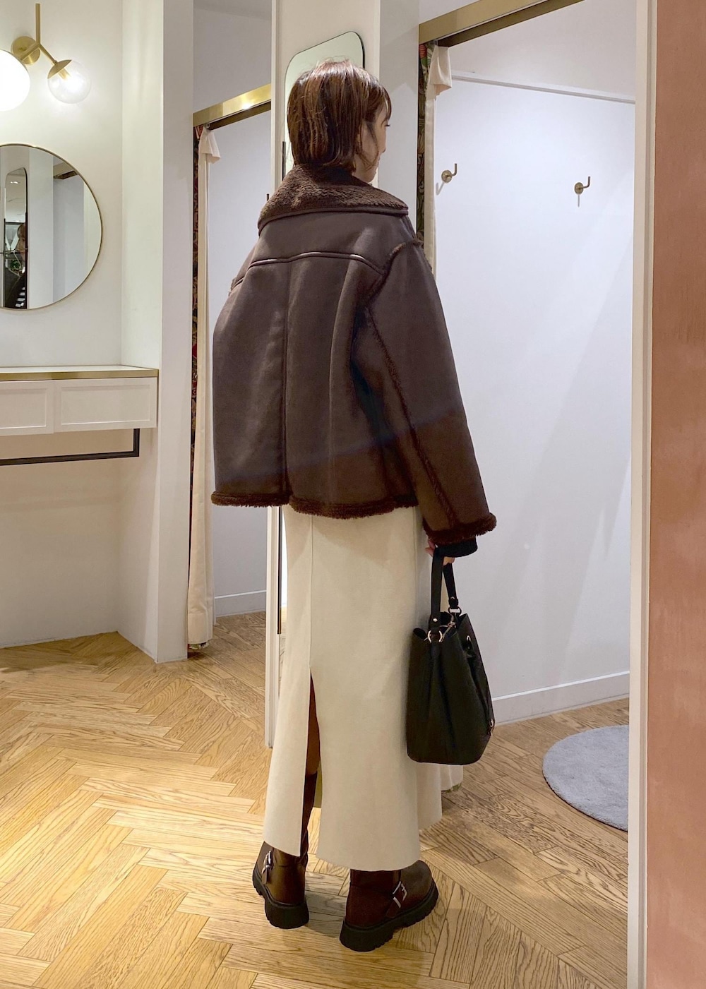 ブラック系のショルダーバッグ、ブラウン系のブーツ、ブラック系のニット/セーターを着用したレディースの秋コーディネートの2枚目の写真