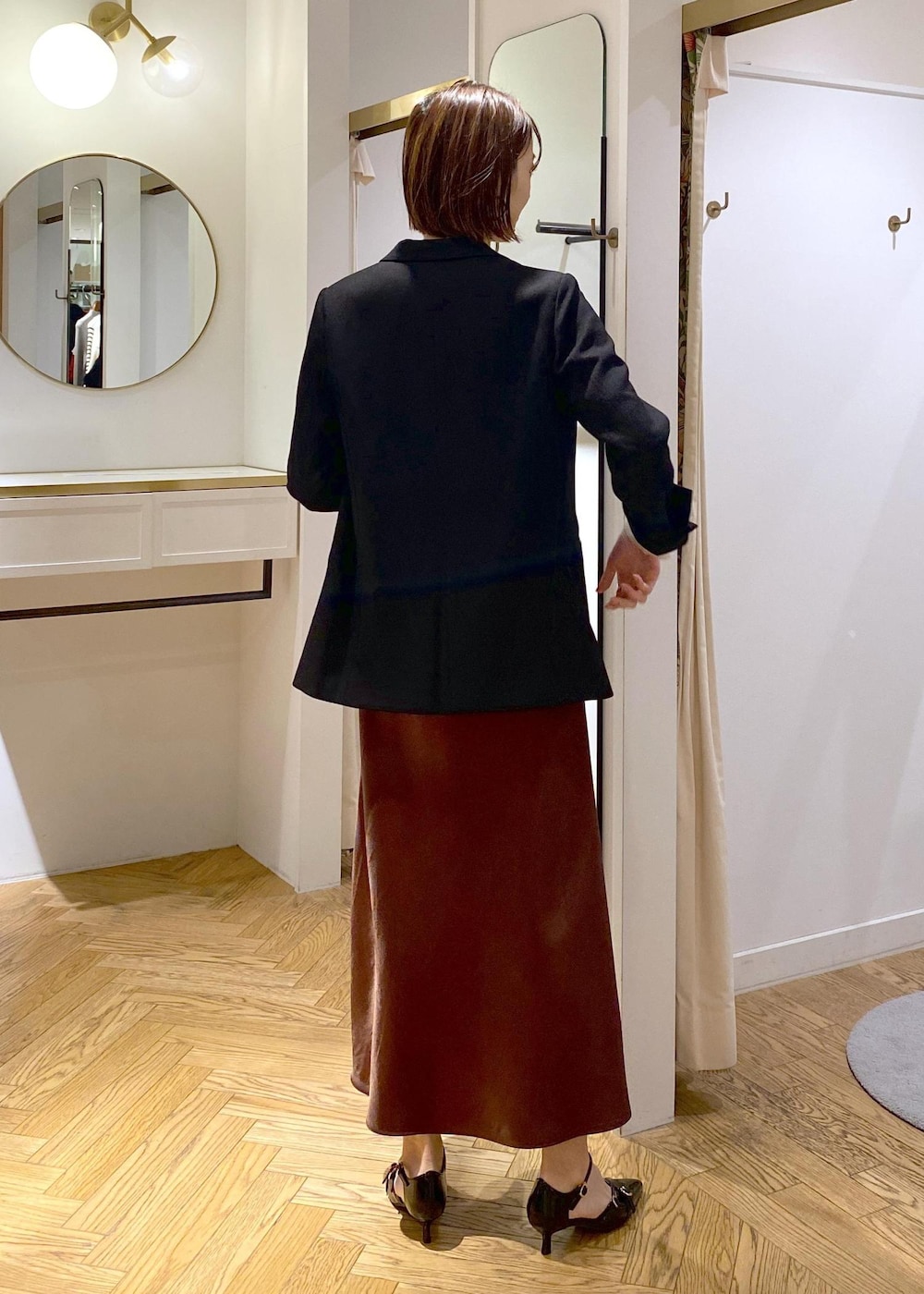 ブラック系のテーラードジャケット、ブラック系のパンプス、ブラウン系のスカートを着用したレディースの冬コーディネートの3枚目の写真