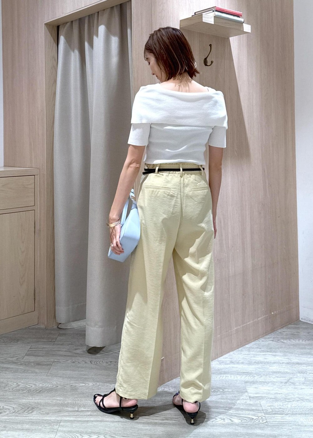 ブルー系のハンドバッグ、ブラック系のサンダル、イエロー系のスラックスを着用したレディースの夏コーディネートの3枚目の写真