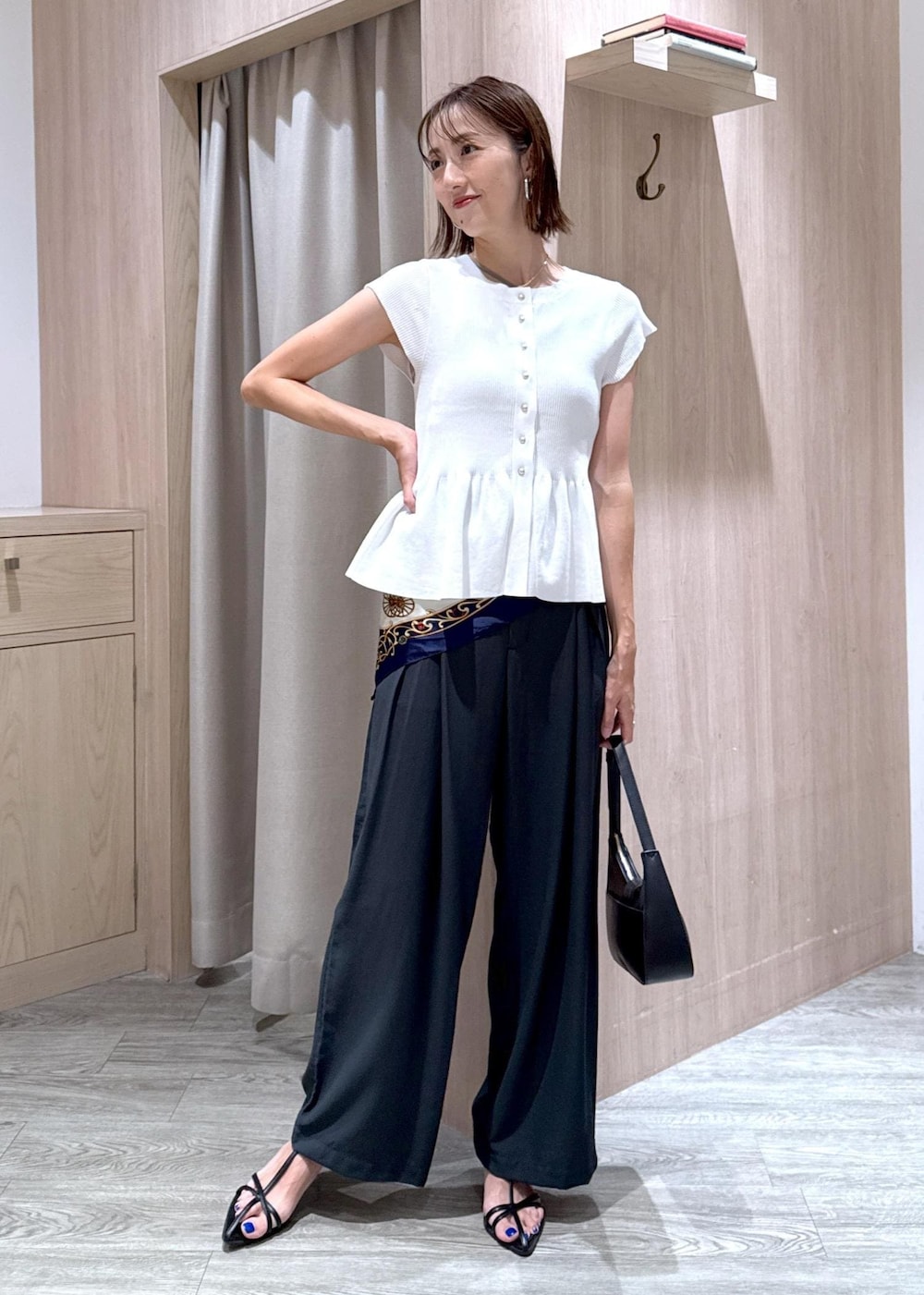 ブラック系のハンドバッグ、ベージュ系のキャミソール、ブラック系のサンダルを着用したレディースの夏コーディネートの3枚目の写真