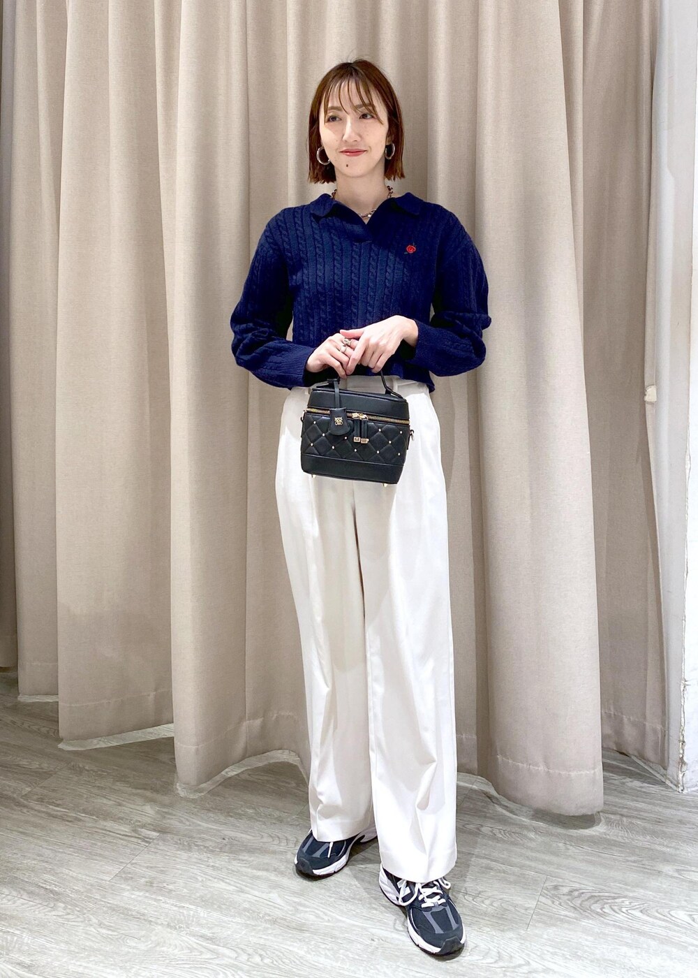 ブラック系のキャミソール、ブラック系のハンドバッグ、ホワイト系のスラックスを着用したレディースの冬コーディネートの4枚目の写真