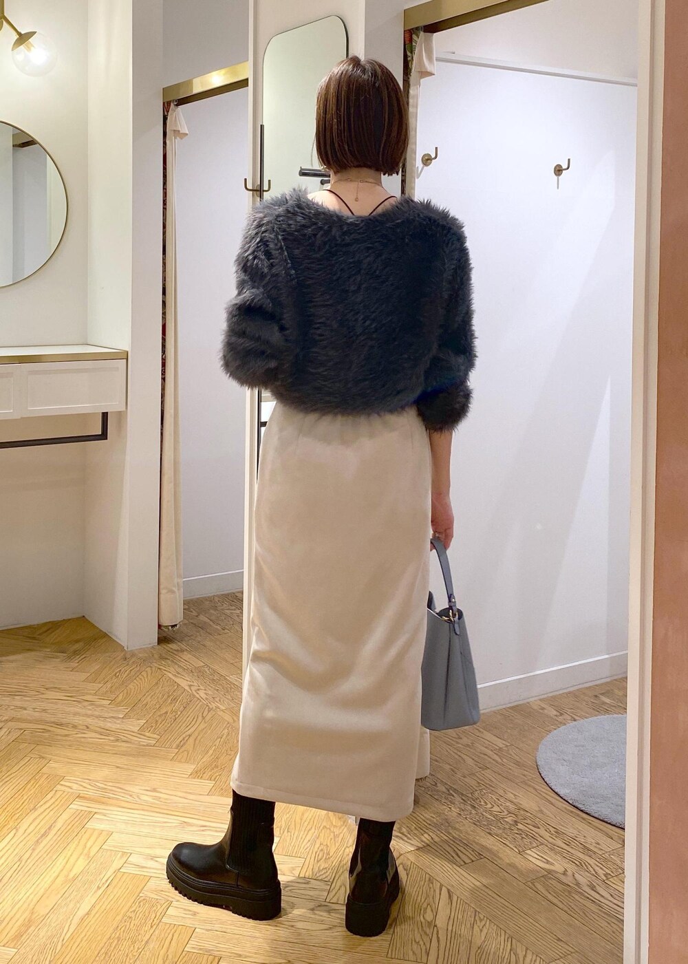 ブラック系のブーツ、ベージュ系のスカート、グレー系のカーディガン/ボレロを着用したレディースの冬コーディネートの2枚目の写真