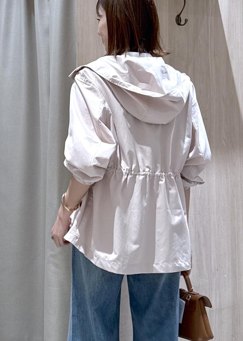 イエロー系のショルダーバッグ、ピンク系のナイロンジャケット、ブルー系のデニムパンツを着用したレディースの春コーディネートの5枚目の写真