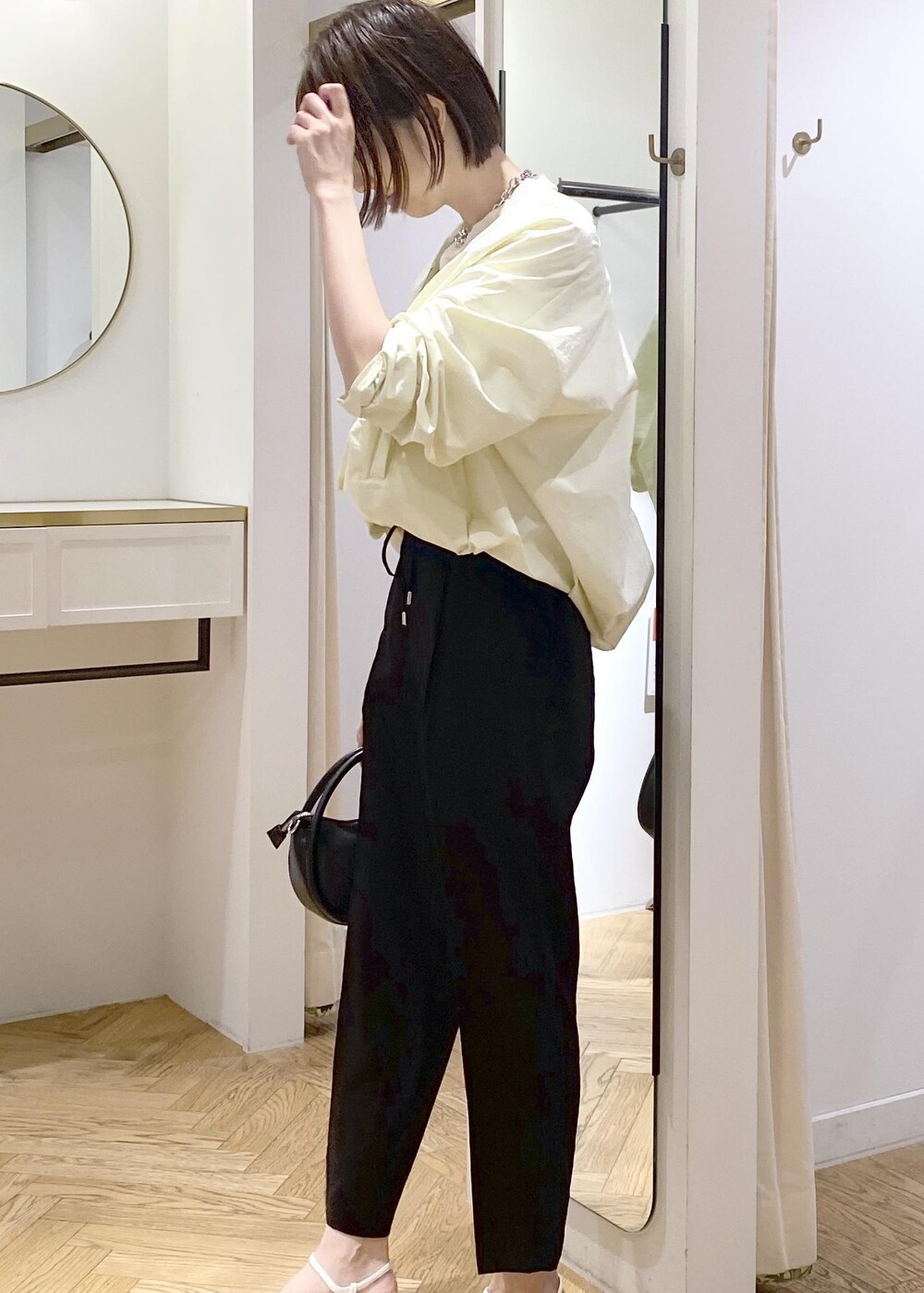 ブラック系のショルダーバッグ、ホワイト系のキャミソール、ブラック系のスラックスを着用したレディースの春コーディネートの3枚目の写真