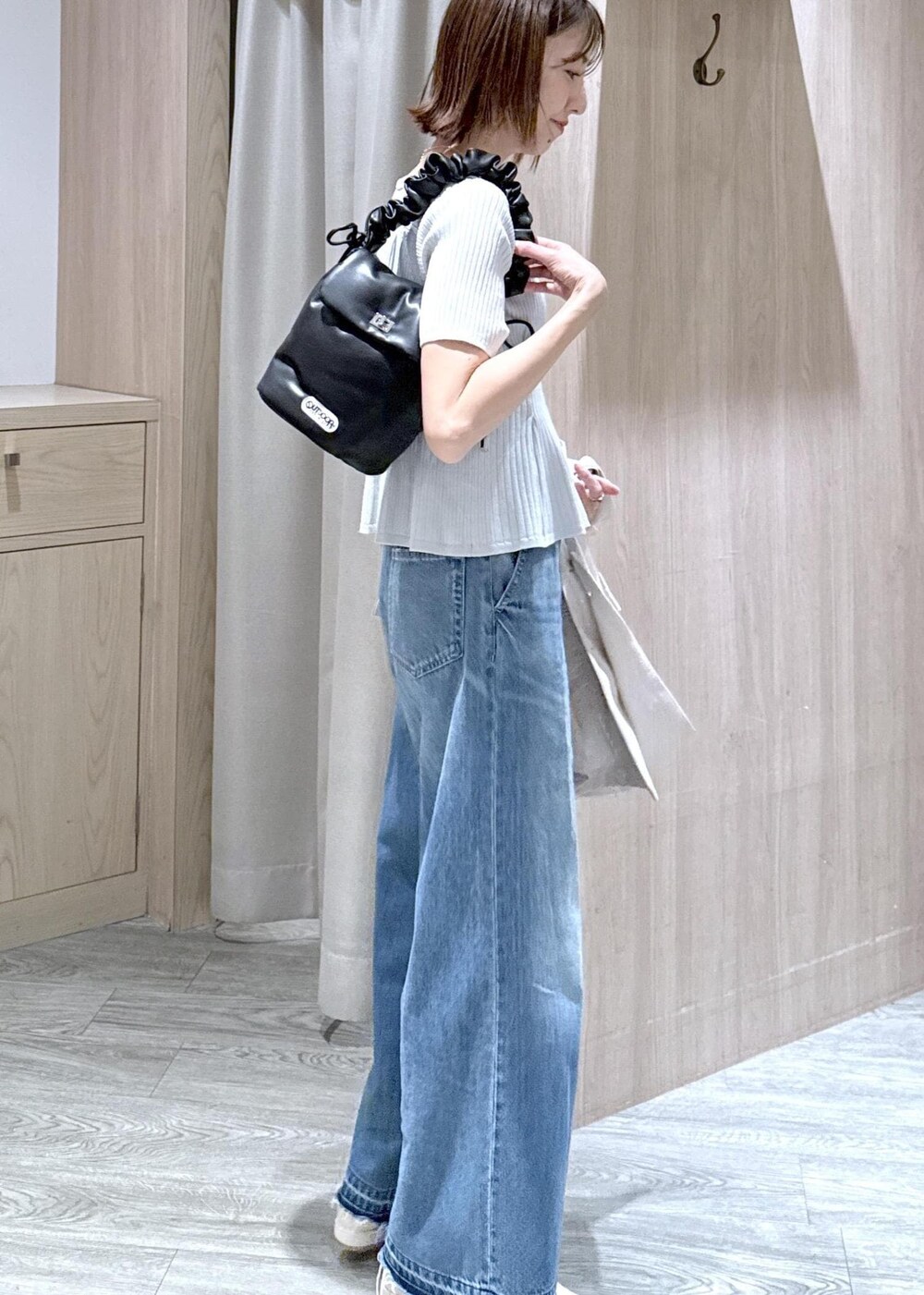 ブルー系のデニムパンツ、ホワイト系のパンプス、ブラック系のショルダーバッグを着用したレディースの春コーディネートの5枚目の写真