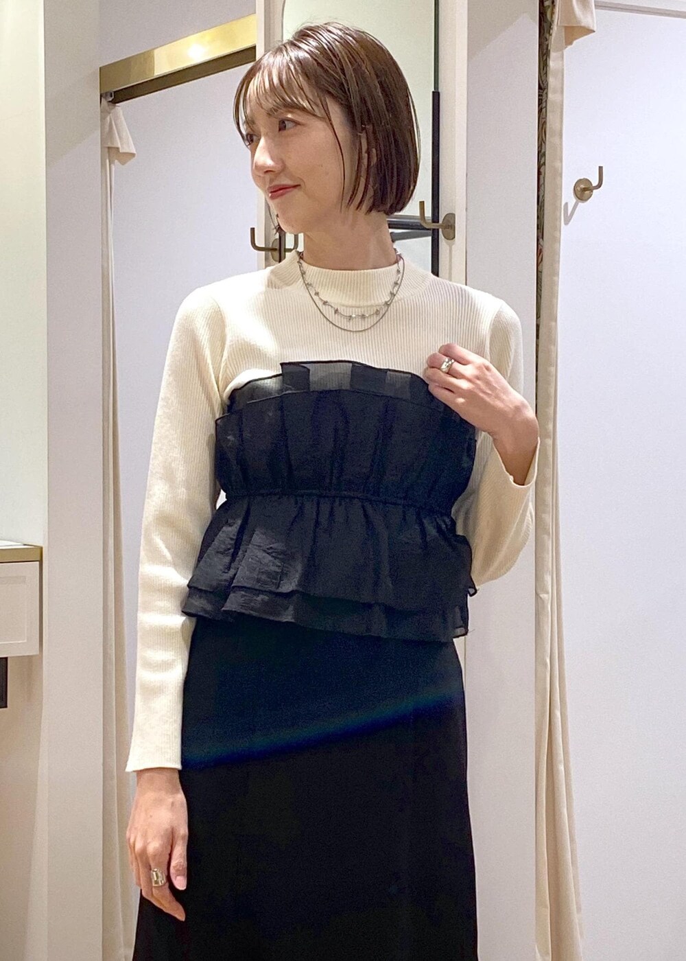 シルバー系のブーツ、ブラック系のスカート、ホワイト系のニット/セーターを着用したレディースの冬コーディネートの7枚目の写真