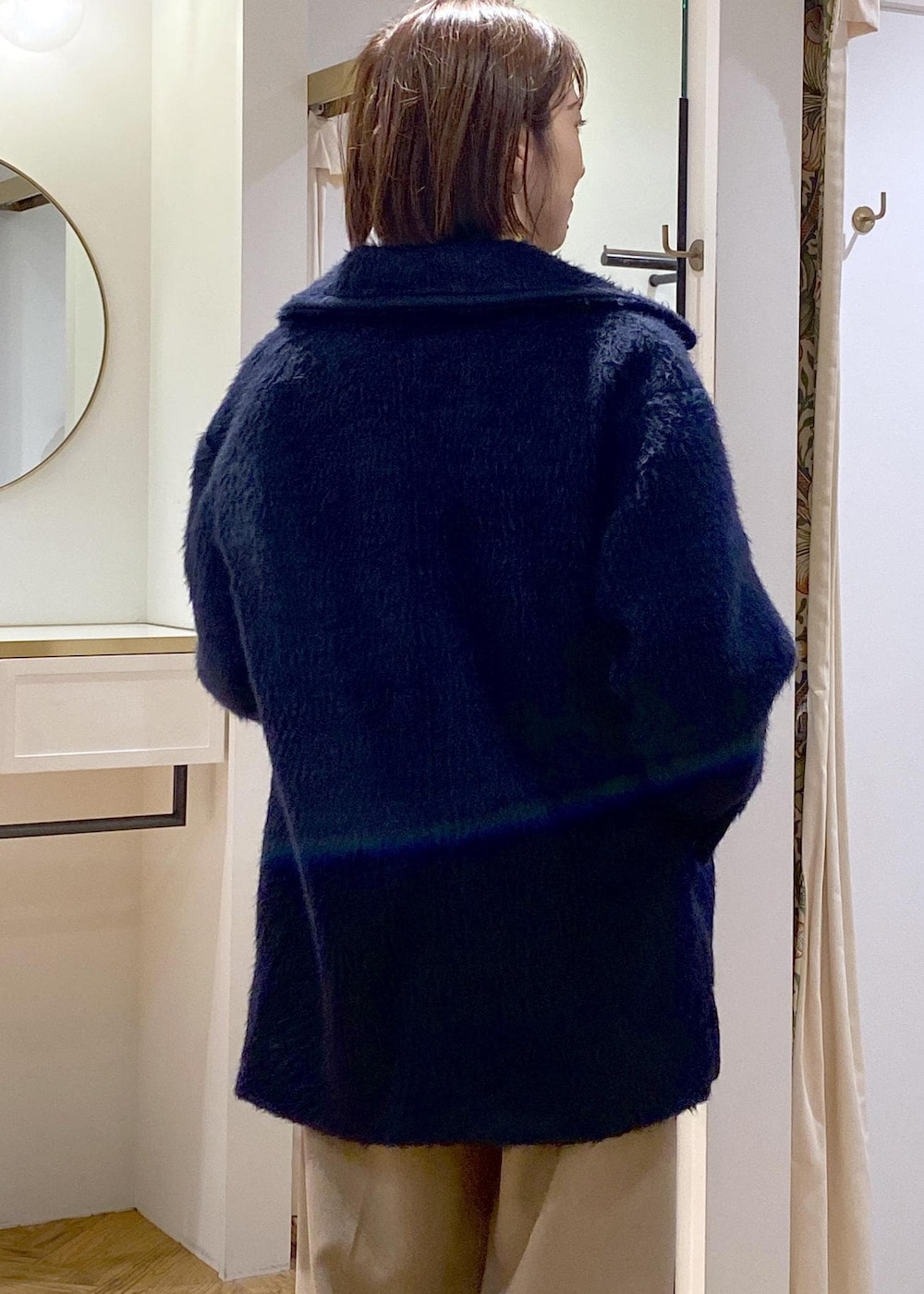 ホワイト系のショルダーバッグ、ベージュ系のスラックス、グレー系のカーディガン/ボレロを着用したレディースの冬コーディネートの7枚目の写真