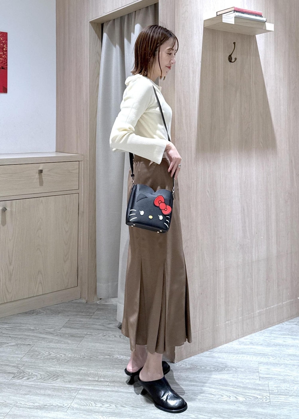 ブラウン系のスカート、ホワイト系のニット/セーター、ブラック系のショルダーバッグを着用したレディースの冬コーディネートの6枚目の写真