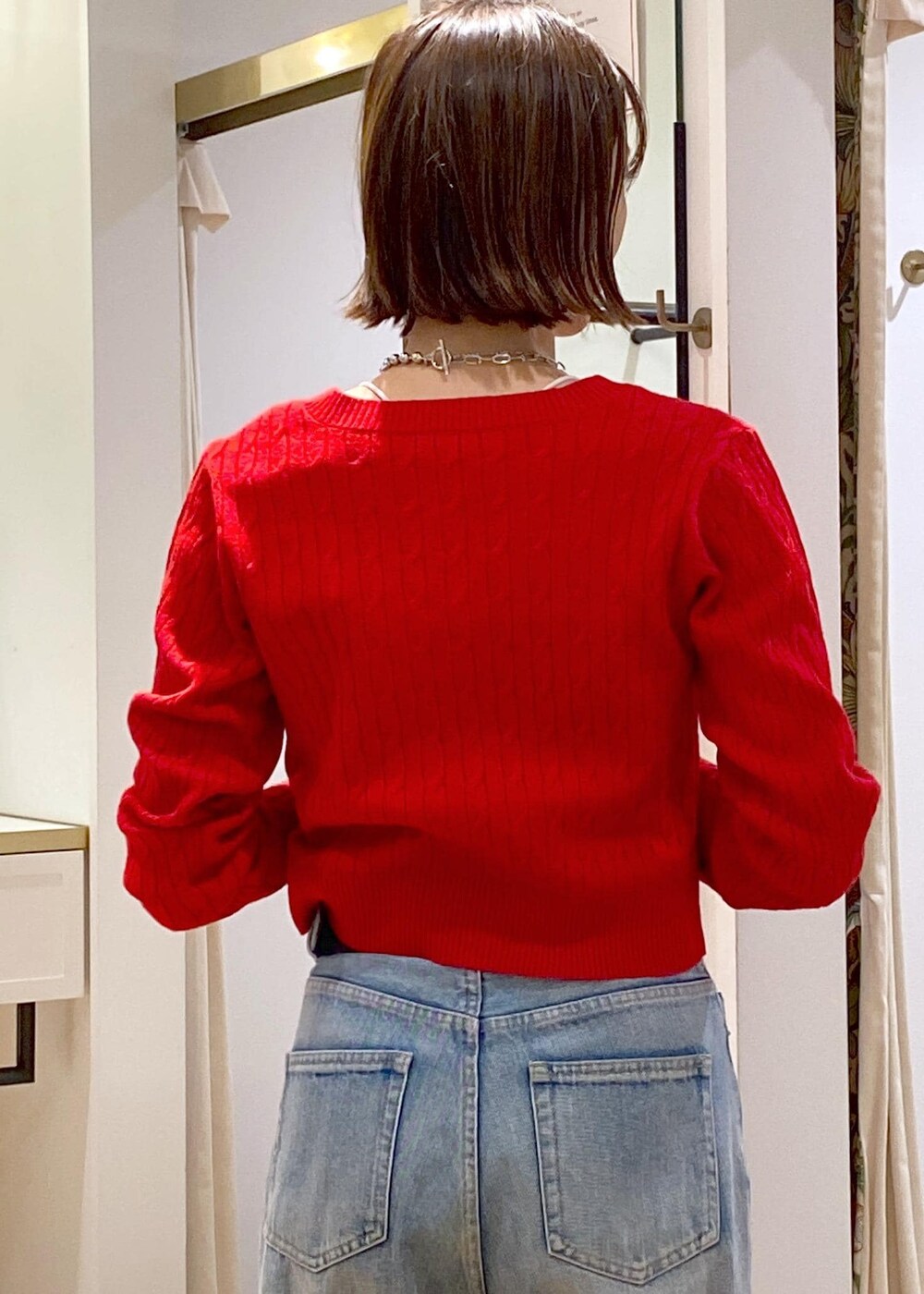 レッド系のニット/セーター、ブルー系のデニムパンツ、ブラック系のベルトを着用したレディースの冬コーディネートの9枚目の写真