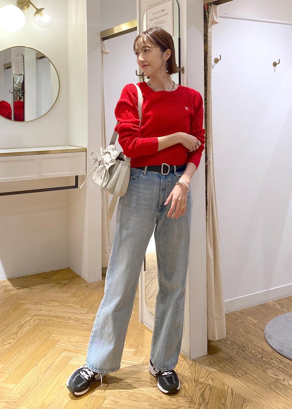 レッド系のニット/セーター、ブルー系のデニムパンツ、ブラック系のベルトを着用したレディースの冬コーディネートの2枚目の写真