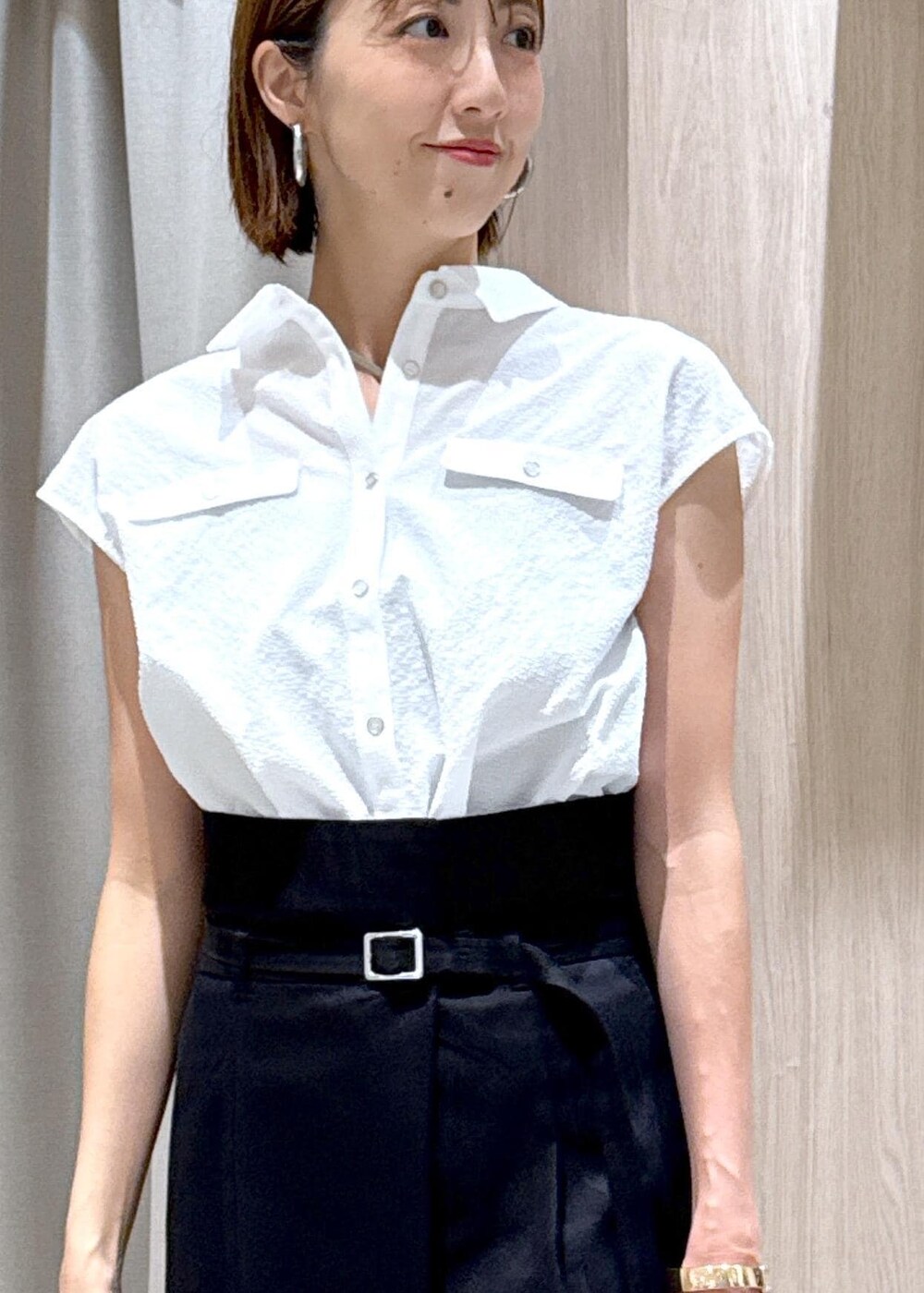 グレー系のハンドバッグ、ブラック系のパンプス、ベージュ系のキャミソールを着用したレディースの夏コーディネートの6枚目の写真