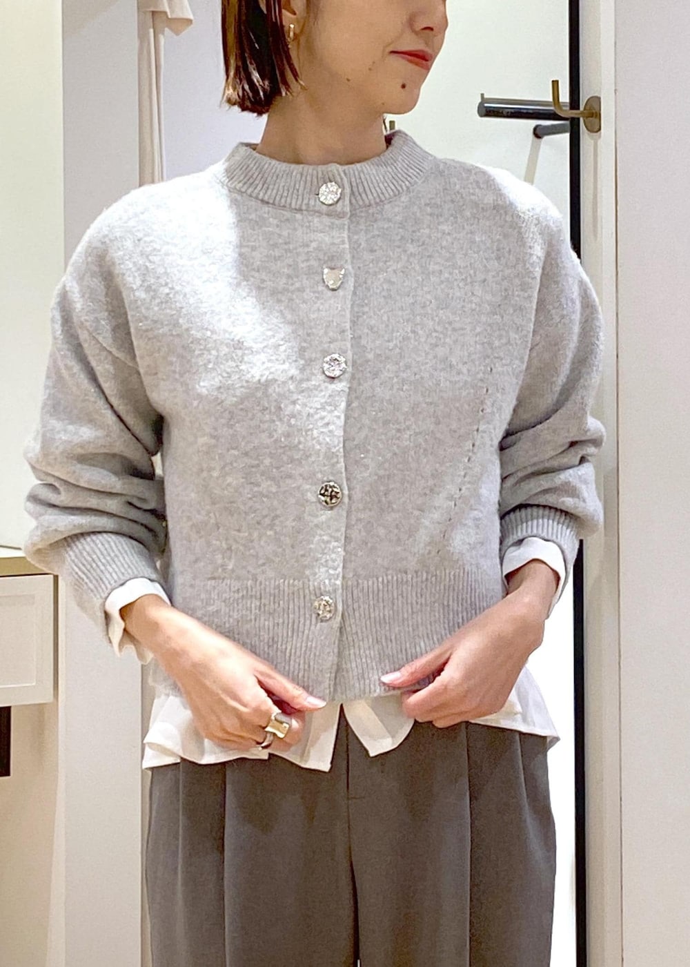 ホワイト系のブーツ、ホワイト系のシャツ/ブラウス、グレー系のカーディガン/ボレロを着用したレディースの冬コーディネートの7枚目の写真