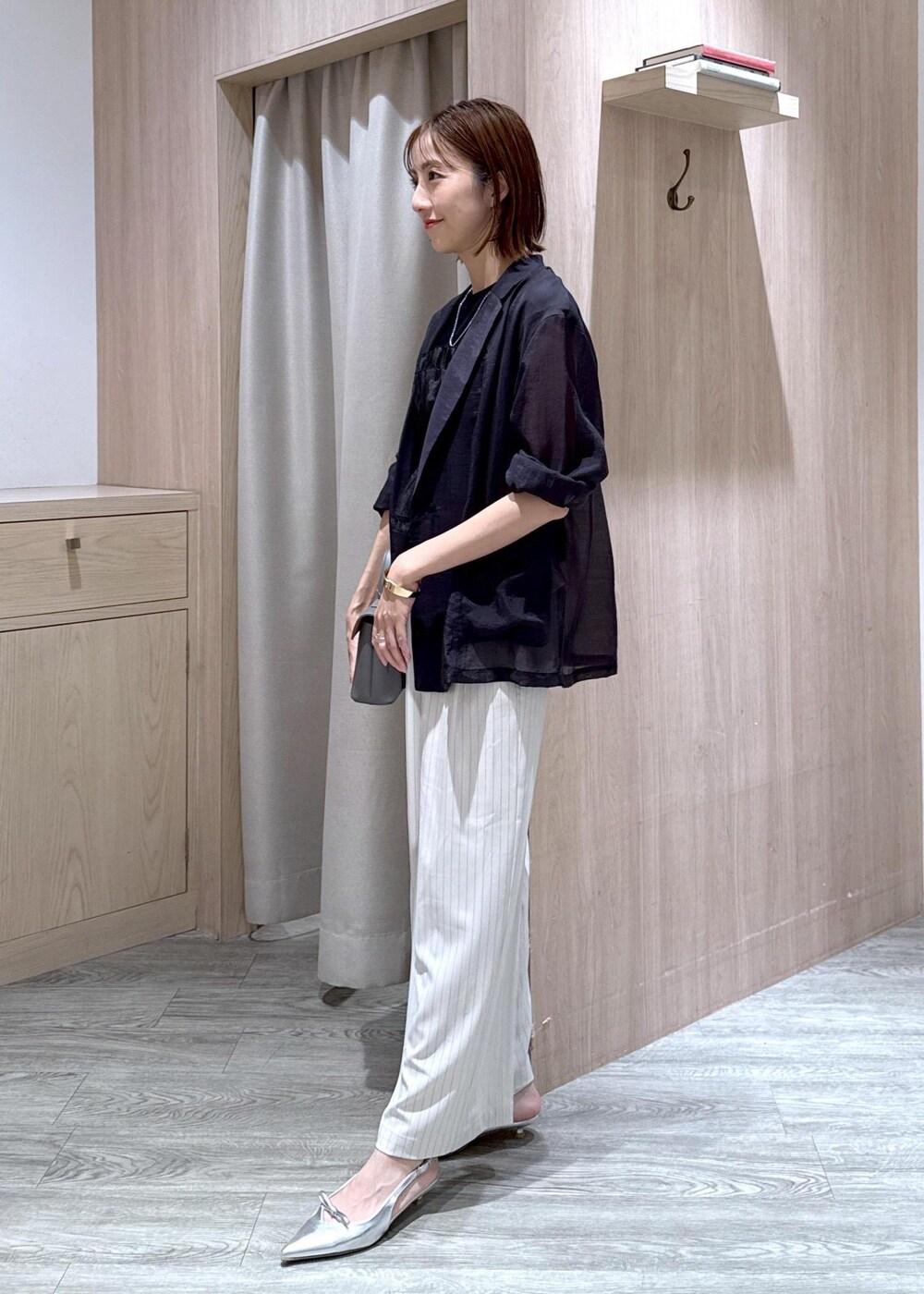 グレー系のショルダーバッグ、シルバー系のパンプス、ブラック系のTシャツ/カットソーを着用したレディースの夏コーディネートの2枚目の写真