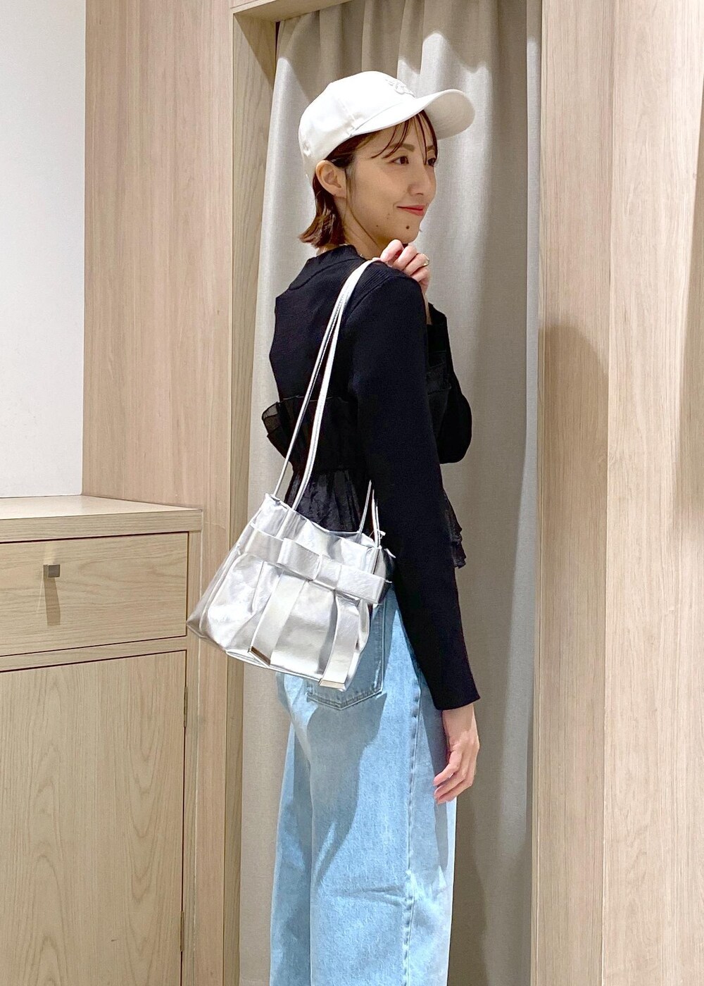 シルバー系のパンプス、ブラック系のニット/セーター、シルバー系のショルダーバッグを着用したレディースの冬コーディネートの6枚目の写真