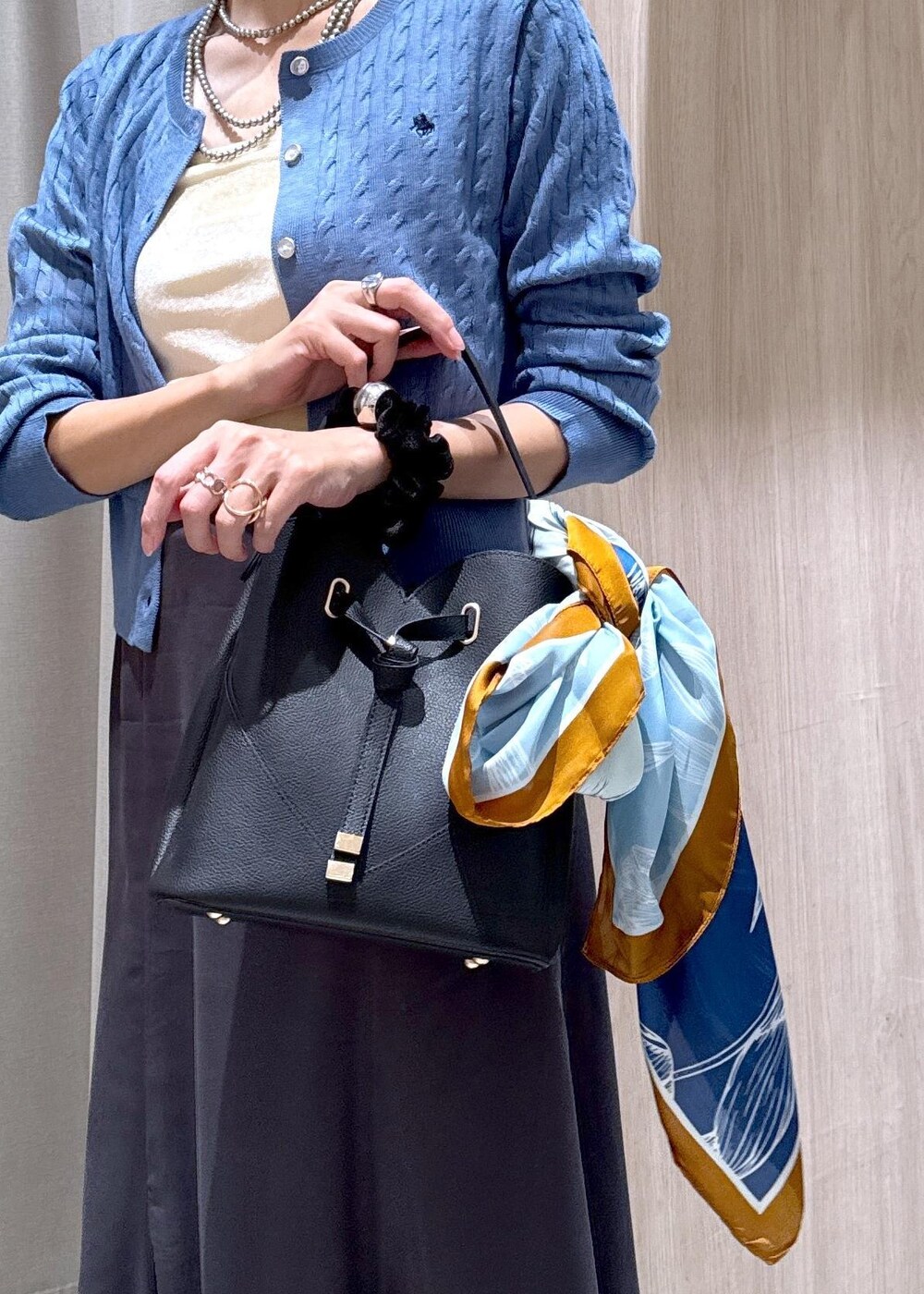 ブラック系のショルダーバッグ、グレー系のスカート、ブルー系のカーディガン/ボレロを着用したレディースの秋コーディネートの7枚目の写真