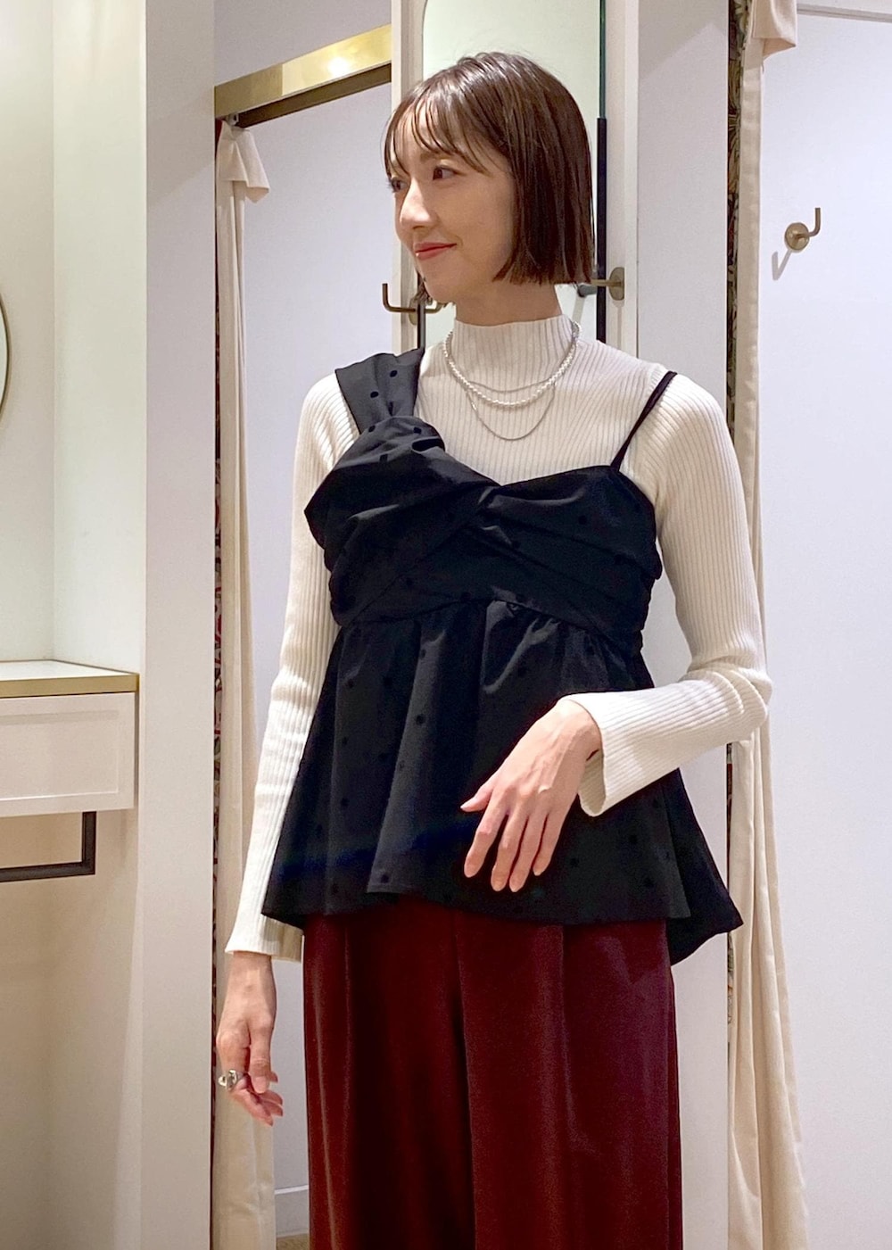 ブラック系のパンプス、ブラック系のキャミソール、ホワイト系のニット/セーターを着用したレディースの冬コーディネートの7枚目の写真