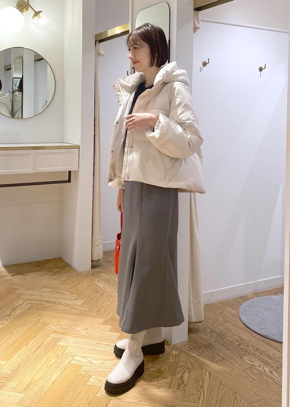 ホワイト系のブーツ、グレー系のスカート、ホワイト系のダウンジャケット/コートを着用したレディースの冬コーディネートの2枚目の写真