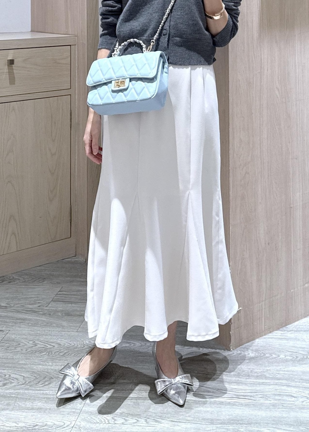 シルバー系のパンプス、ホワイト系のキャミソール、ホワイト系のスカートを着用したレディースの冬コーディネートの6枚目の写真