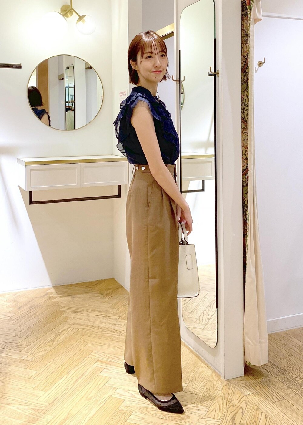 ブラック系のパンプス、ホワイト系のキャミソール、ホワイト系のハンドバッグを着用したレディースの春コーディネートの2枚目の写真