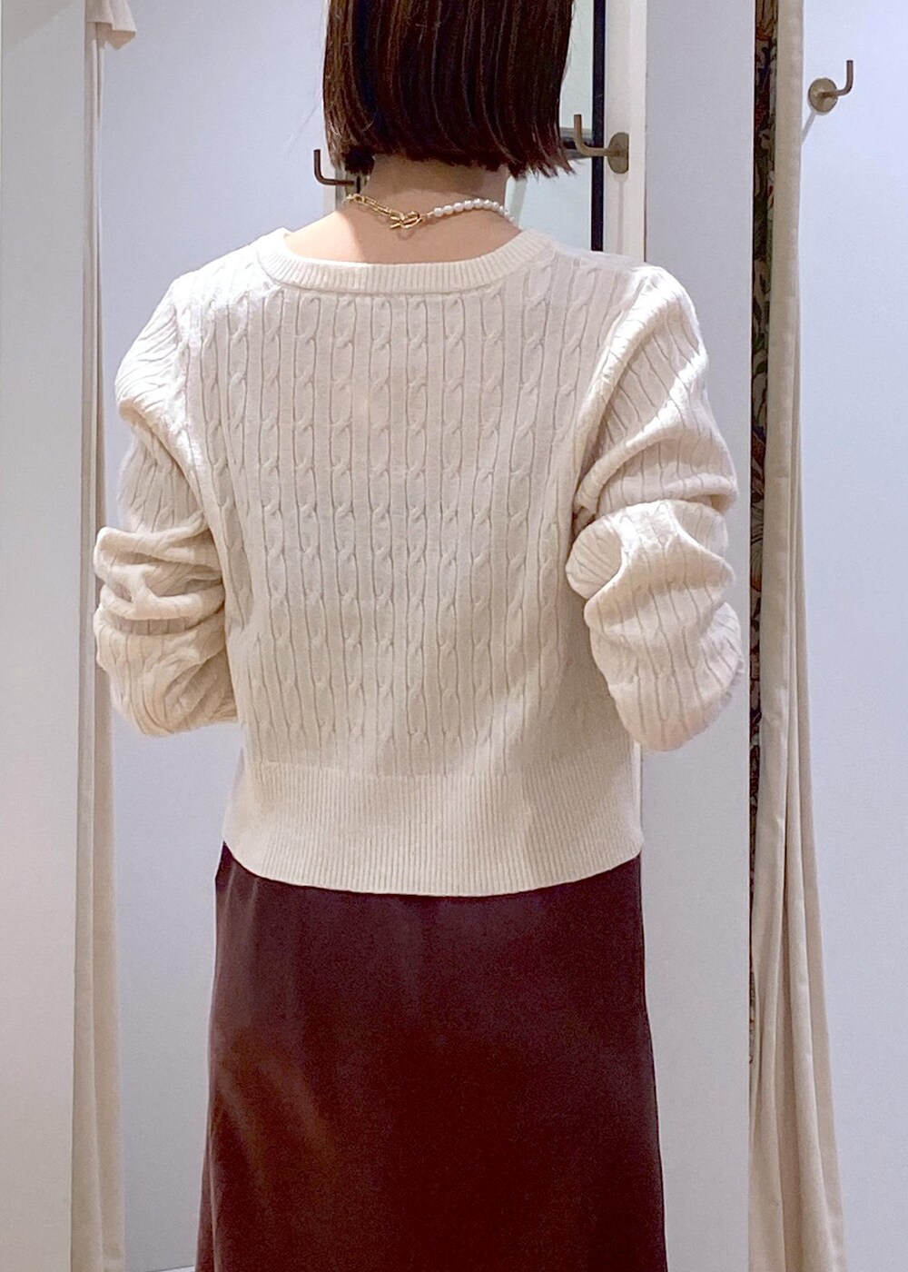 ブラウン系のスカート、ホワイト系のカーディガン/ボレロ、ブラック系のパンプスを着用したレディースの冬コーディネートの7枚目の写真