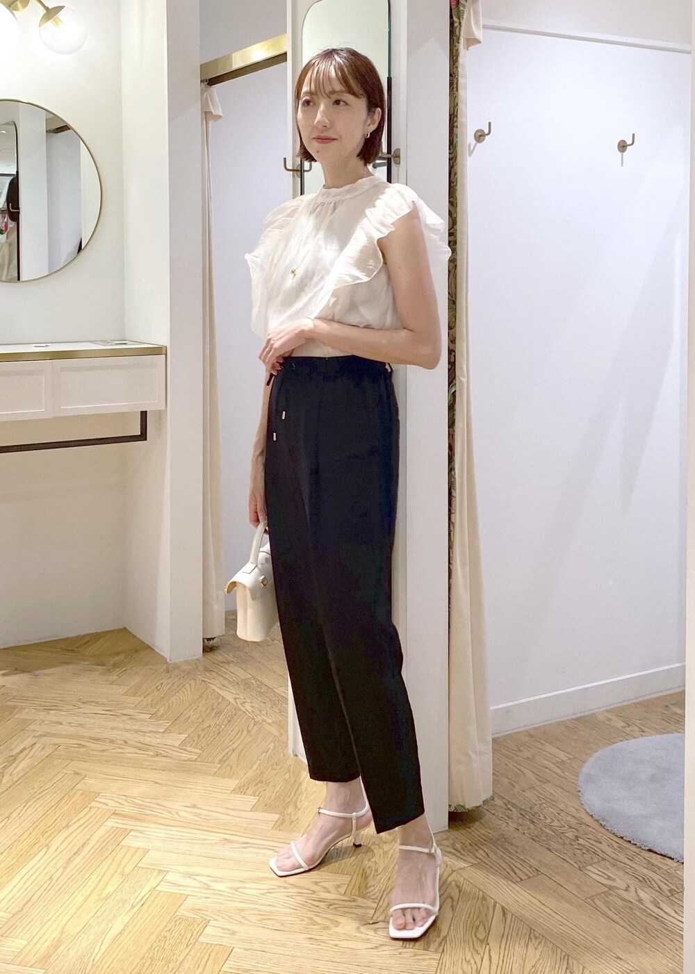 ブラック系のキャミソール、ホワイト系のショルダーバッグ、ブラック系のスラックスを着用したレディースの夏コーディネートの7枚目の写真