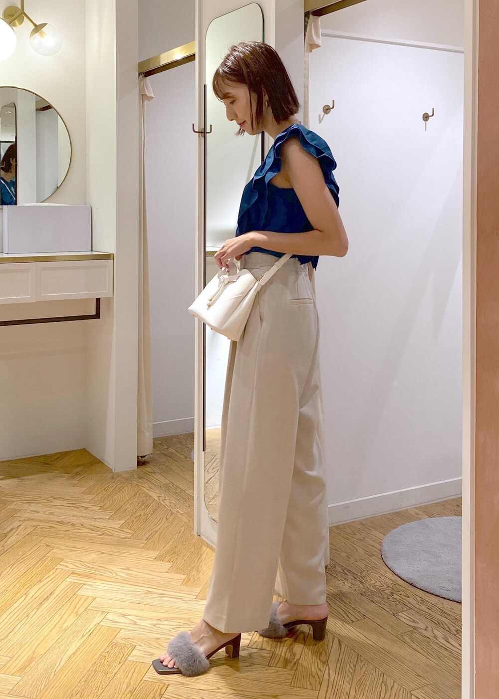 ホワイト系のスラックス、ホワイト系のショルダーバッグ、グレー系のドレスシューズを着用したレディースの夏コーディネートの5枚目の写真