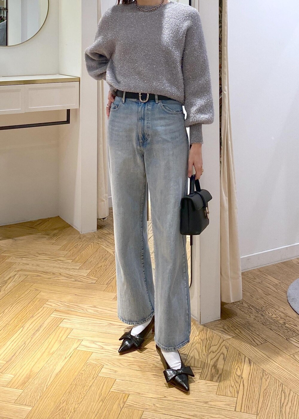 ブラック系のパンプス、グレー系のニット/セーター、ブルー系のデニムパンツを着用したレディースの冬コーディネートの6枚目の写真