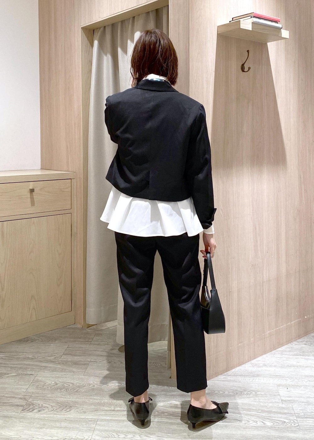 ブラック系のパンプス、ホワイト系のカーディガン/ボレロ、ブラック系のハンドバッグを着用したレディースの冬コーディネートの3枚目の写真