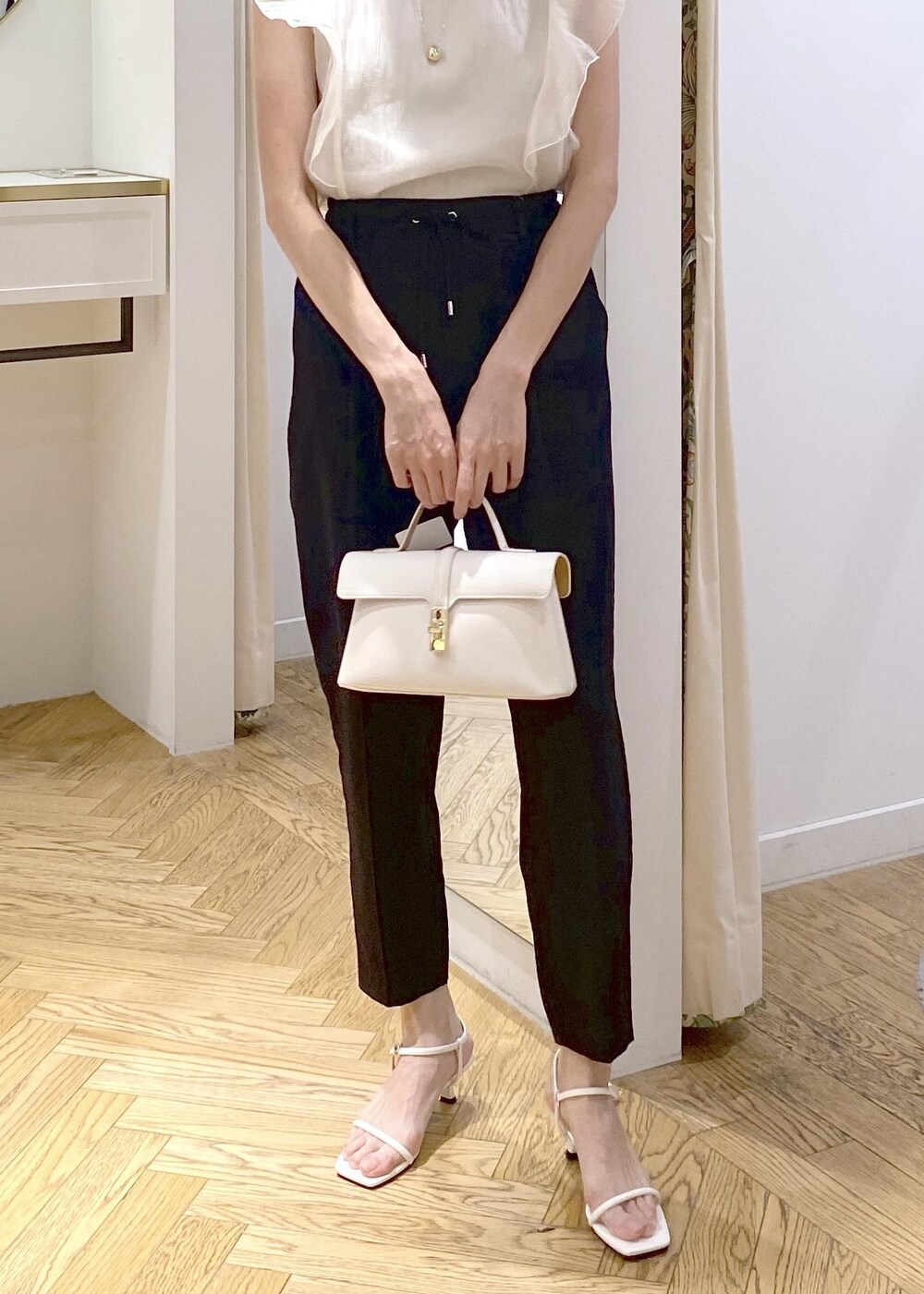 ブラック系のキャミソール、ホワイト系のショルダーバッグ、ブラック系のスラックスを着用したレディースの夏コーディネートの3枚目の写真