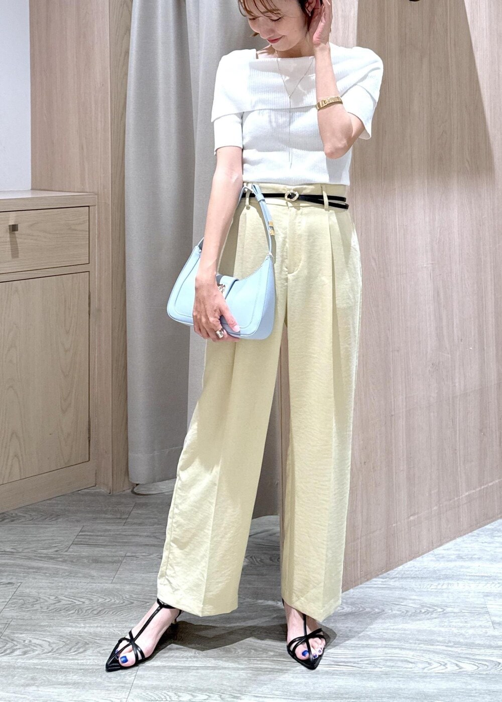 ブルー系のハンドバッグ、ブラック系のサンダル、イエロー系のスラックスを着用したレディースの夏コーディネートの5枚目の写真
