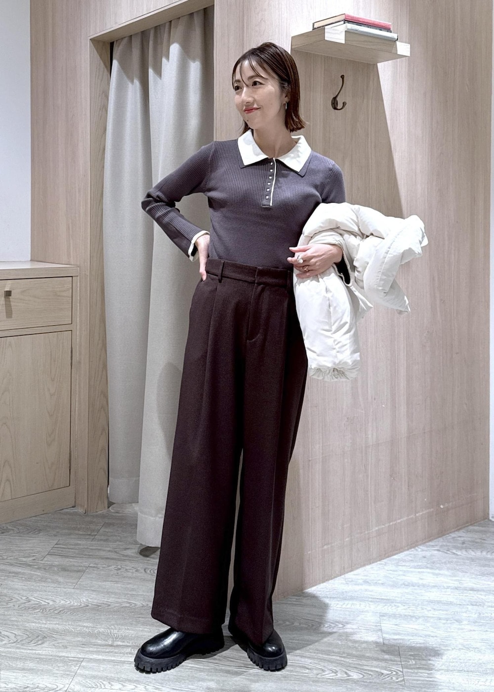 ブラウン系のスラックス、ブラック系のショルダーバッグ、ホワイト系のダウンジャケット/コートを着用したレディースの冬コーディネートの4枚目の写真