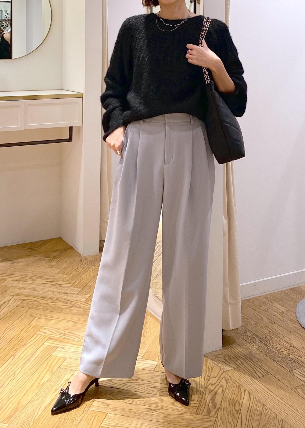 ブルー系のスラックス、ブラック系のパンプス、ブラック系のショルダーバッグを着用したレディースの冬コーディネートの6枚目の写真