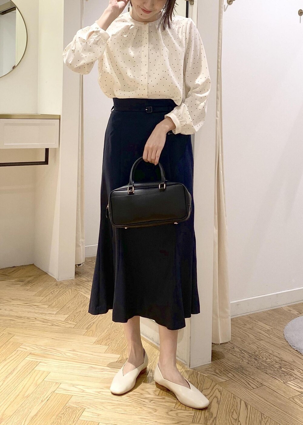 ホワイト系のパンプス、ブラック系のボストンバッグ、ホワイト系のシャツ/ブラウスを着用したレディースの春コーディネートの3枚目の写真