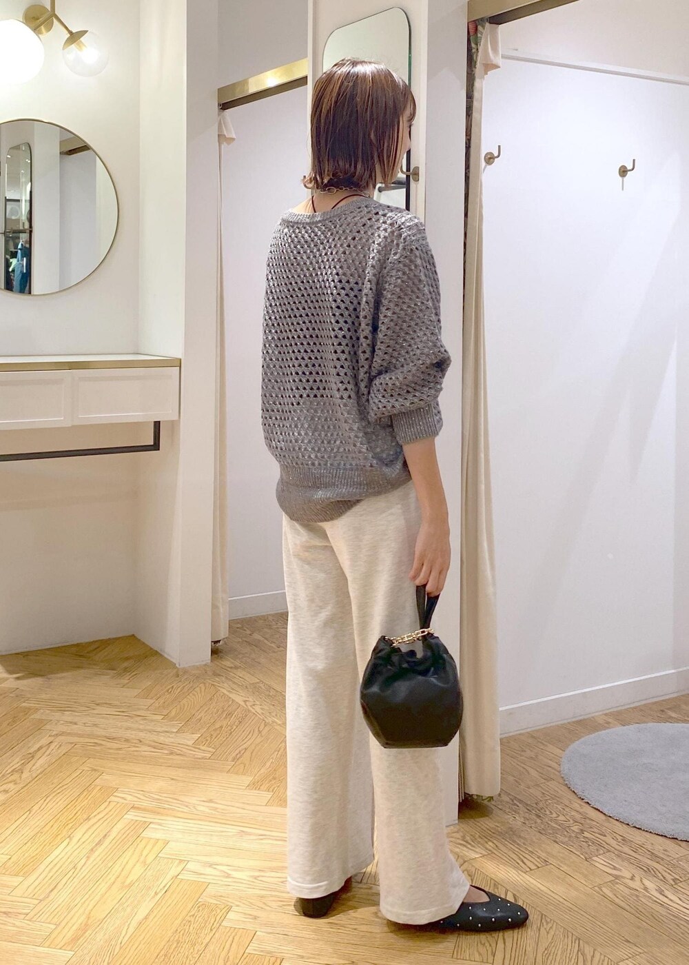 ホワイト系のその他パンツ、グレー系のニット/セーター、ブラック系のハンドバッグを着用したレディースの秋コーディネートの2枚目の写真
