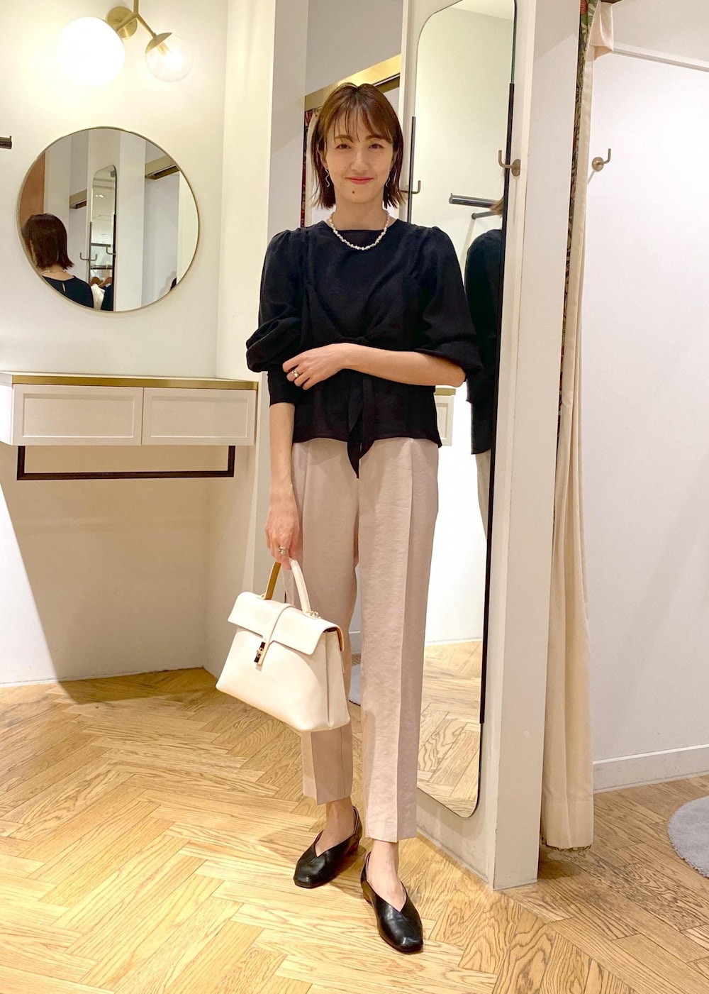 ブラック系のパンプス、ホワイト系のハンドバッグ、ブラック系のシャツ/ブラウスを着用したレディースの春コーディネートの5枚目の写真