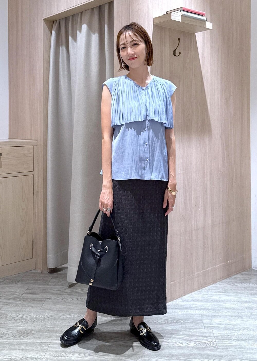 ブラック系のショルダーバッグ、ブラック系のローファー、グレー系のスカートを着用したレディースの夏コーディネートの9枚目の写真