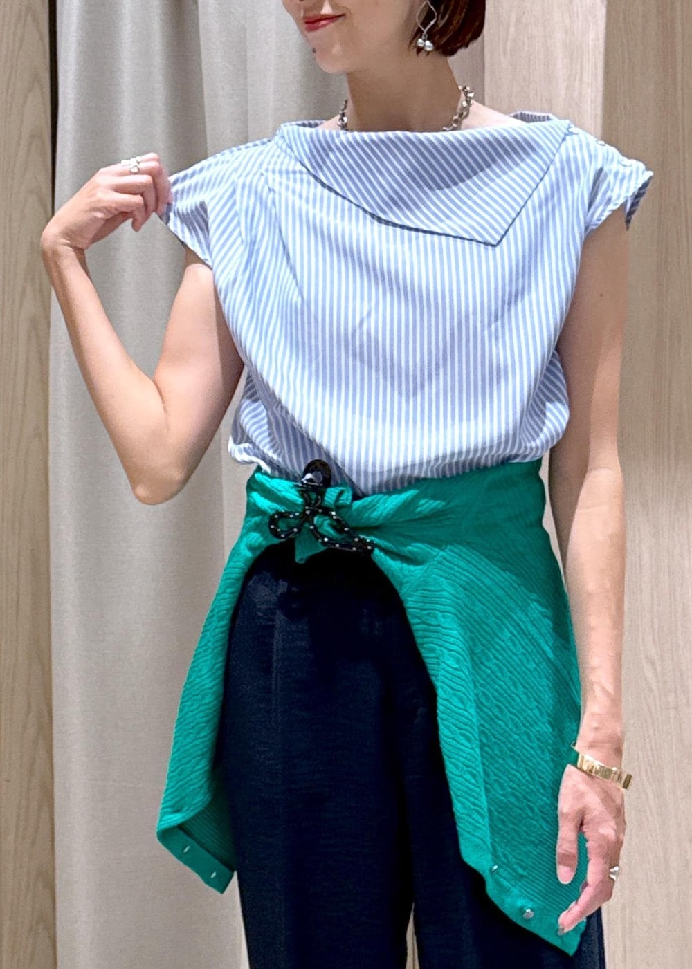 シルバー系のパンプス、ブラック系のハンドバッグ、ブルー系のスラックスを着用したレディースの夏コーディネートの6枚目の写真