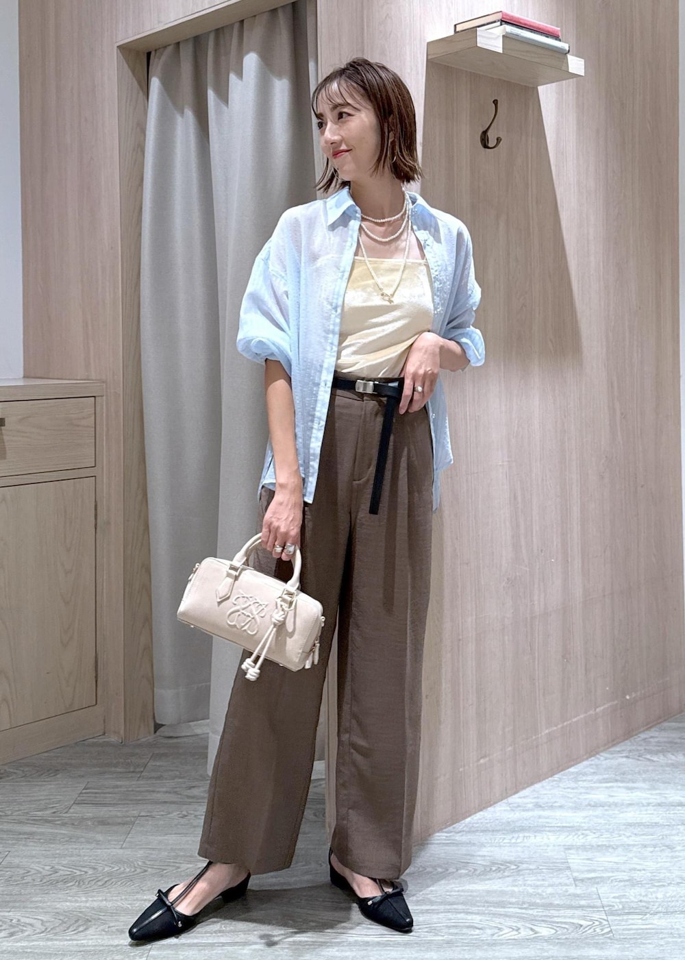 グリーン系のスラックス、ブラック系のパンプス、ベージュ系のボストンバッグを着用したレディースの秋コーディネートの2枚目の写真